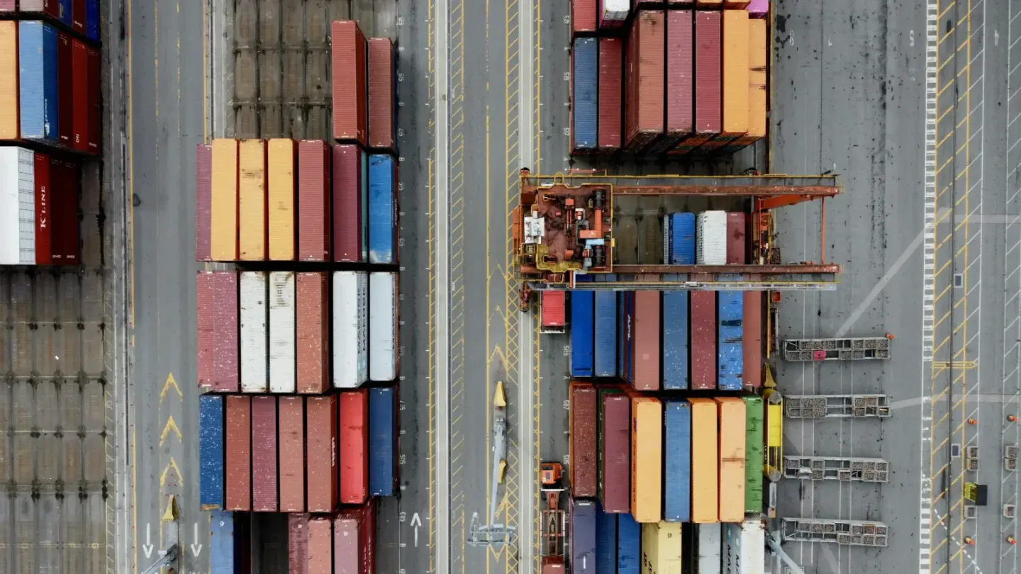 Overhead view of stacked shipping containers and handling cranes at an export container terminal