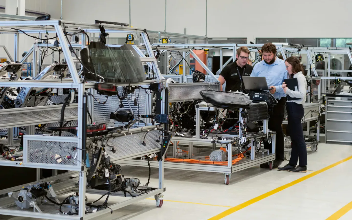 Production engineers reviewing assembly progress alongside industrial equipment on the factory floor