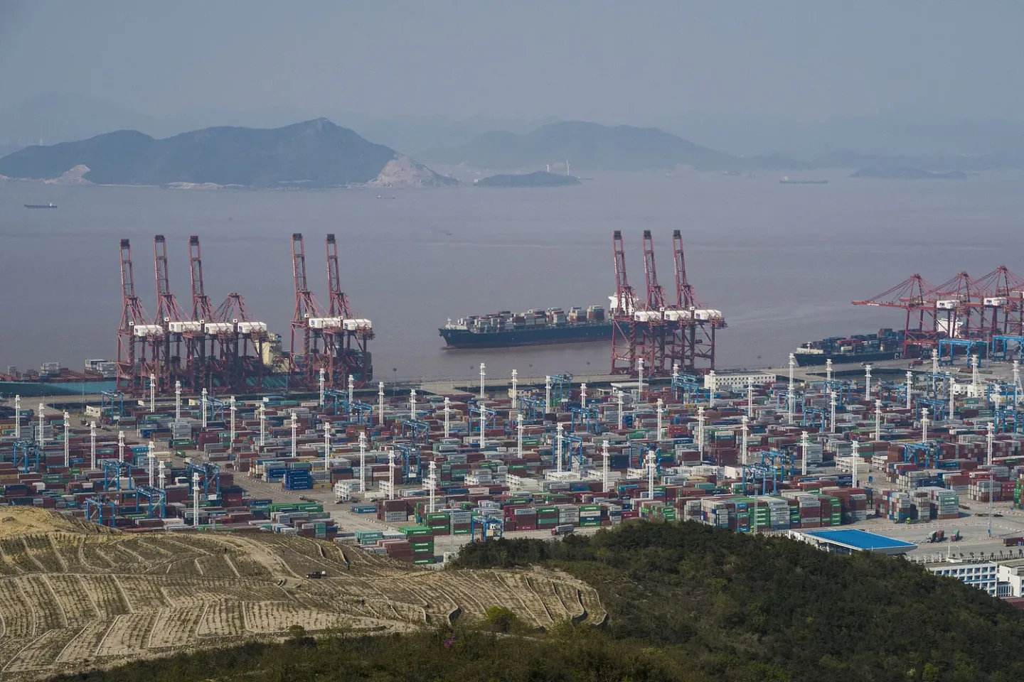 Container vessel, gantry cranes, and stacked export containers at Beilun Port, Ningbo-Zhoushan Port, China